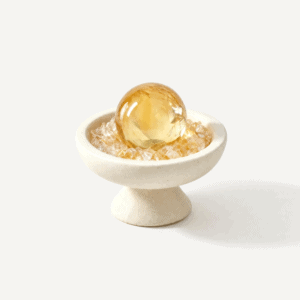 Golden citrine sphere in a white bowl for abundance and positivity.