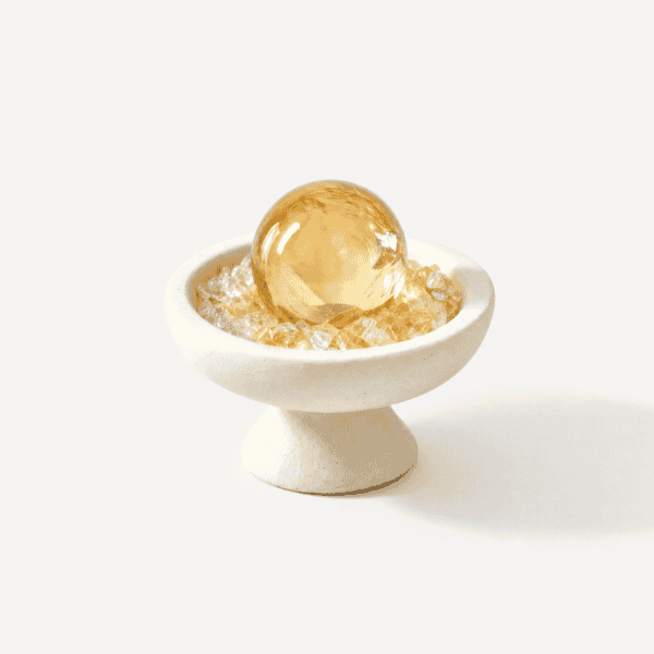 Golden citrine sphere in a white bowl for abundance and positivity.