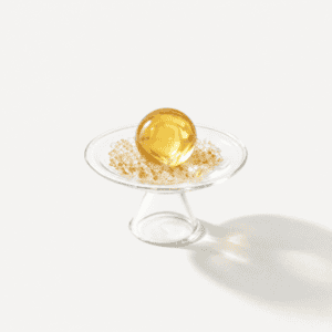 Golden sphere on glass stand with decorative base for prosperity decor.